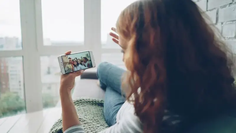 Woman on a couch having a video chat call on her phone